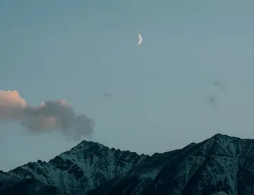 Mountain range under a crescent moon