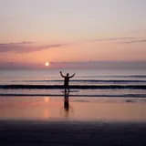 Person standing on a beach at sunset